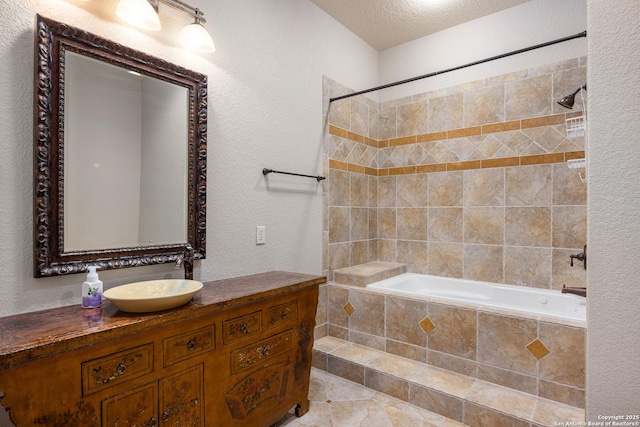 bathroom featuring a textured ceiling, vanity, and tiled shower / bath