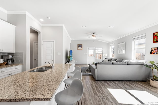 kitchen with white cabinetry, a center island with sink, a breakfast bar area, and tasteful backsplash