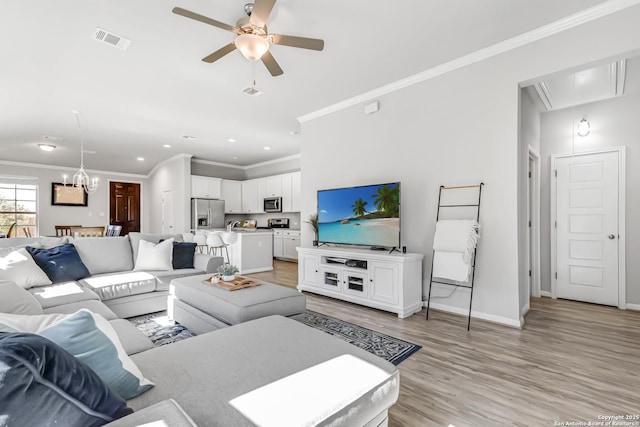 living room featuring crown molding, ceiling fan with notable chandelier, and light hardwood / wood-style flooring