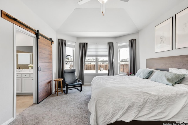 bedroom with a barn door, light carpet, ceiling fan, connected bathroom, and lofted ceiling