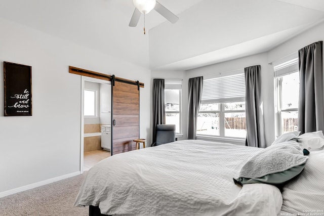 bedroom with ceiling fan, ensuite bathroom, a barn door, and light carpet