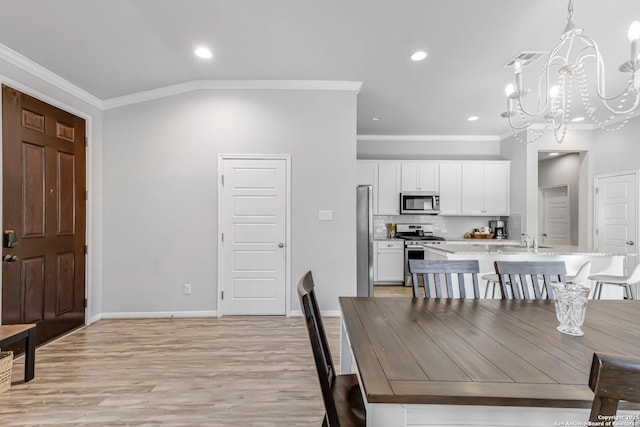 dining space featuring lofted ceiling, crown molding, a notable chandelier, and light wood-type flooring