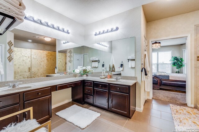 bathroom with a shower with door, tile patterned floors, and vanity