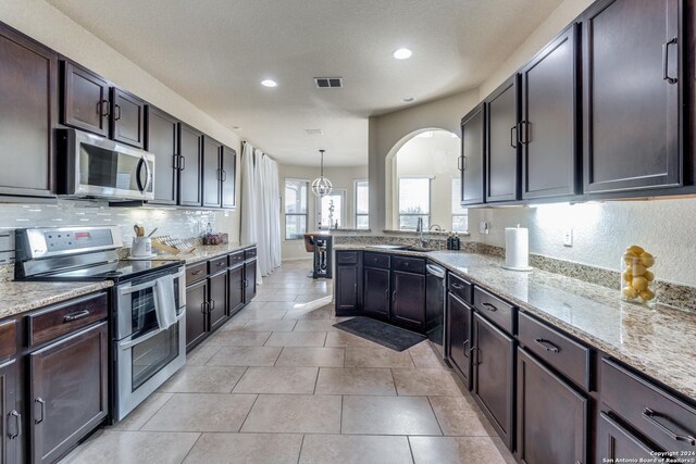 kitchen featuring dark brown cabinets, decorative light fixtures, sink, light tile patterned flooring, and stainless steel appliances