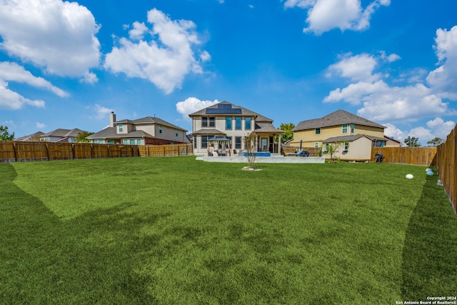 rear view of house with a patio area, a yard, and solar panels