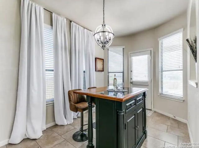 kitchen featuring decorative light fixtures, light tile patterned floors, a kitchen bar, a center island, and an inviting chandelier