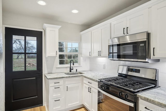 kitchen featuring light stone counters, sink, white cabinetry, and appliances with stainless steel finishes