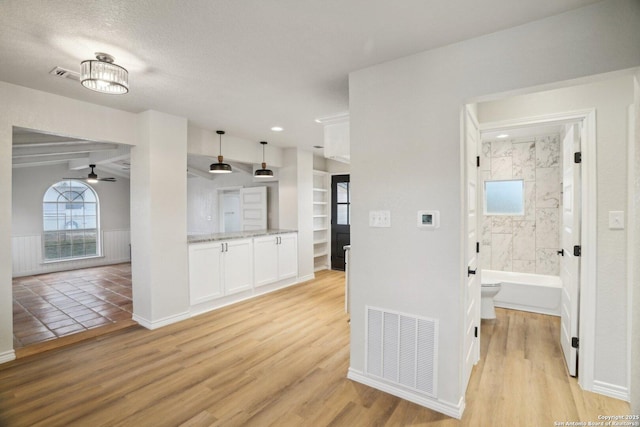 kitchen featuring light hardwood / wood-style floors, light stone countertops, pendant lighting, and white cabinets