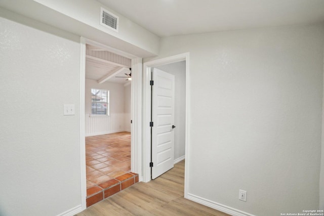 corridor featuring light hardwood / wood-style flooring and vaulted ceiling with beams