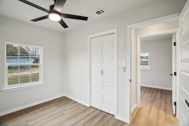 unfurnished bedroom with ceiling fan, light hardwood / wood-style floors, and multiple windows