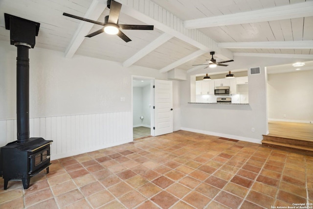 unfurnished living room with wood ceiling, light tile patterned floors, a wood stove, vaulted ceiling with beams, and ceiling fan