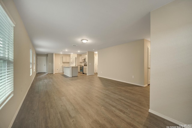 unfurnished living room with dark hardwood / wood-style flooring and a healthy amount of sunlight