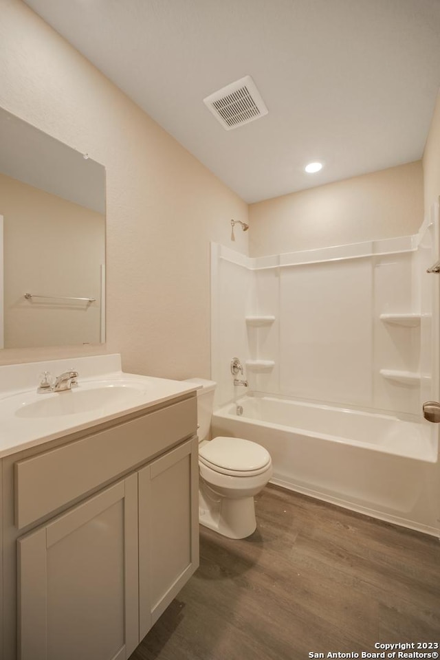 full bathroom with wood-type flooring, shower / bathtub combination, toilet, and vanity