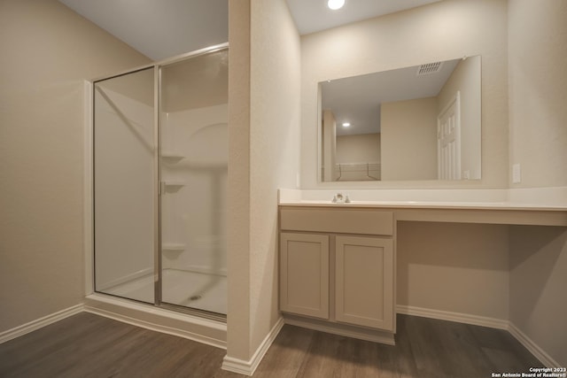 bathroom featuring wood-type flooring, a shower with door, and vanity