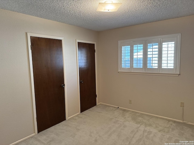 unfurnished bedroom featuring light colored carpet, a textured ceiling, and a closet