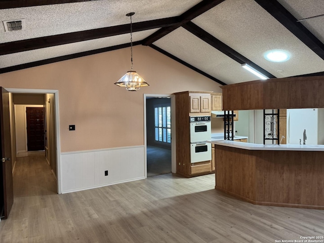 kitchen with a textured ceiling, white appliances, decorative light fixtures, light hardwood / wood-style floors, and lofted ceiling with beams