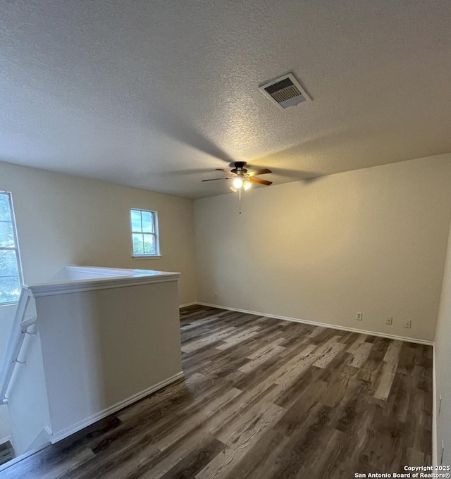 empty room with ceiling fan, a textured ceiling, and dark hardwood / wood-style flooring