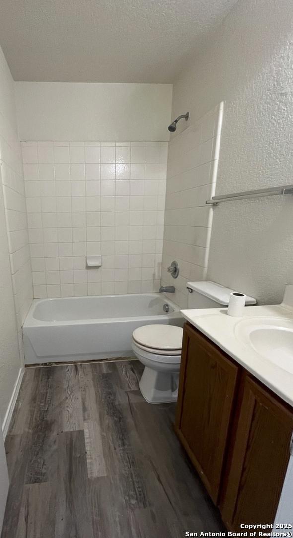 full bathroom featuring hardwood / wood-style flooring, tiled shower / bath, toilet, a textured ceiling, and vanity