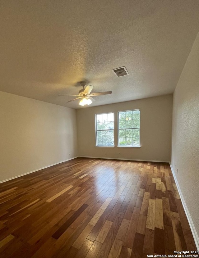 empty room featuring ceiling fan, a textured ceiling, and dark hardwood / wood-style flooring