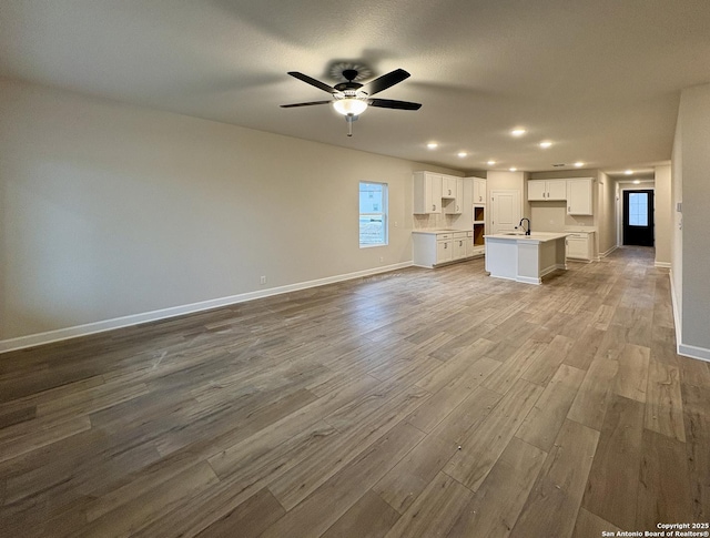 unfurnished living room featuring ceiling fan and light wood-type flooring