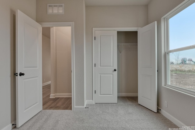 unfurnished bedroom with light colored carpet and a closet