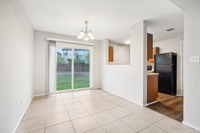 unfurnished dining area with an inviting chandelier and light tile patterned floors