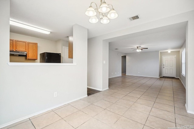 tiled spare room with ceiling fan with notable chandelier