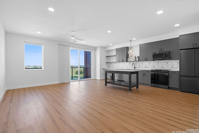 kitchen with appliances with stainless steel finishes, decorative backsplash, sink, light hardwood / wood-style flooring, and pendant lighting