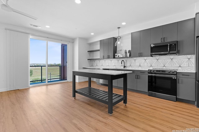 kitchen featuring decorative light fixtures, light wood-type flooring, tasteful backsplash, and appliances with stainless steel finishes