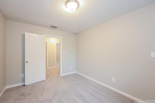 carpeted empty room featuring a textured ceiling