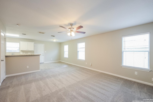 unfurnished living room featuring ceiling fan, plenty of natural light, and light carpet