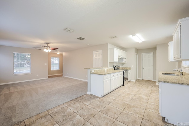 kitchen featuring light stone countertops, white cabinets, light carpet, sink, and electric range