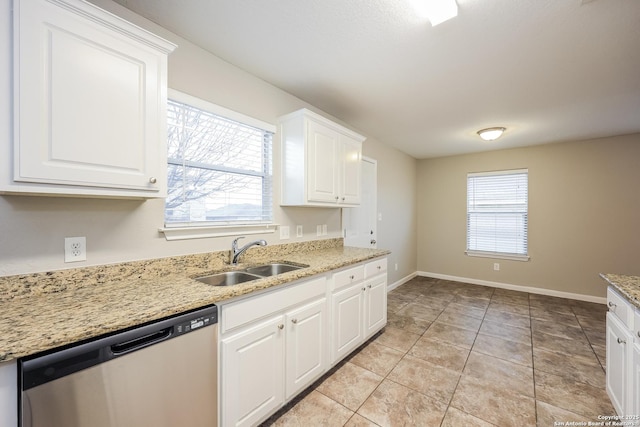 kitchen featuring light stone countertops, white cabinets, dishwasher, sink, and light tile patterned floors