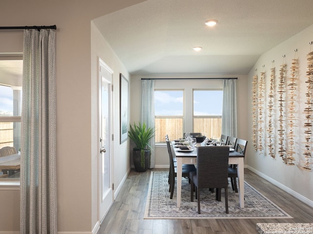 dining space featuring hardwood / wood-style floors and vaulted ceiling