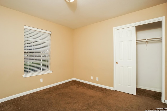 unfurnished bedroom featuring a closet and dark carpet