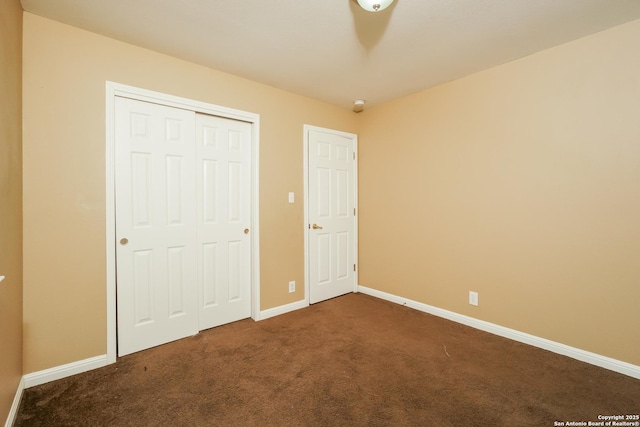 unfurnished bedroom with dark colored carpet and a closet