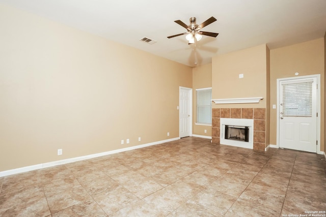 unfurnished living room with ceiling fan and a tile fireplace