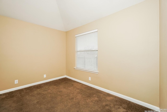 empty room featuring dark carpet and lofted ceiling