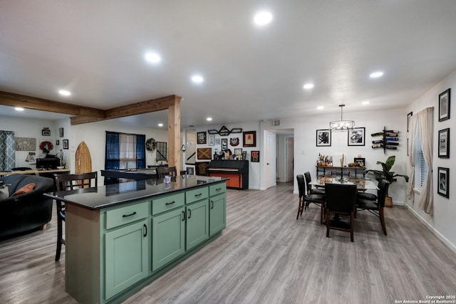 kitchen featuring light hardwood / wood-style flooring, green cabinets, decorative light fixtures, beam ceiling, and a kitchen island