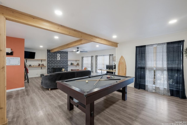 playroom featuring ceiling fan, hardwood / wood-style flooring, beam ceiling, billiards, and a large fireplace