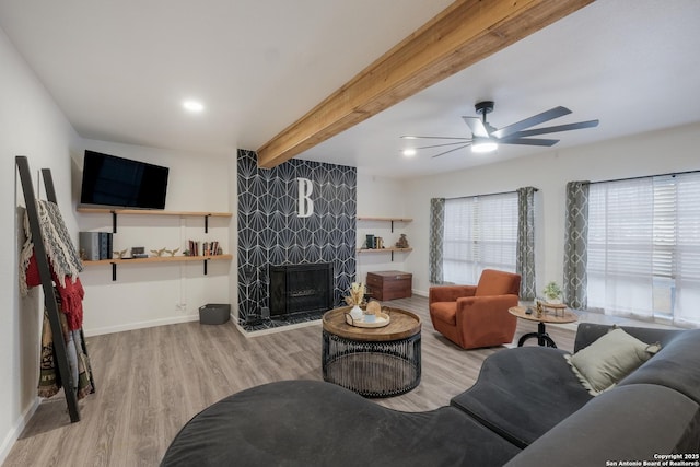 living room with light hardwood / wood-style floors, beamed ceiling, and ceiling fan