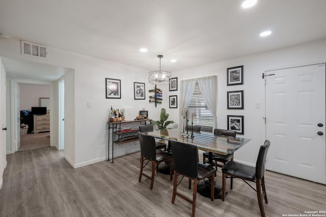 dining space with light wood-type flooring and a notable chandelier