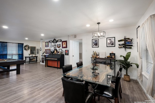 dining area with hardwood / wood-style flooring, a notable chandelier, and pool table