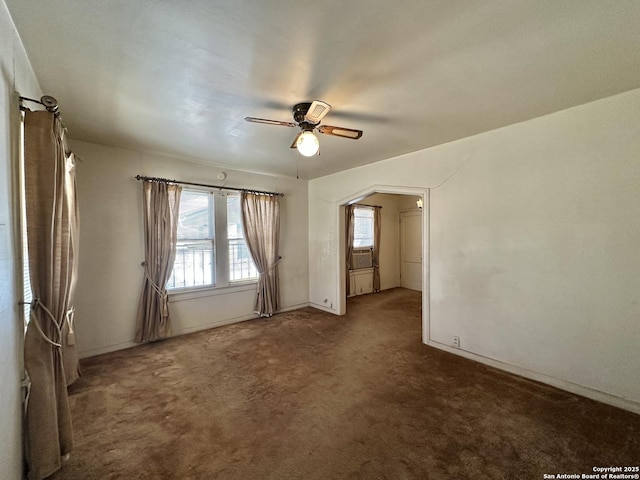 empty room featuring ceiling fan and dark carpet