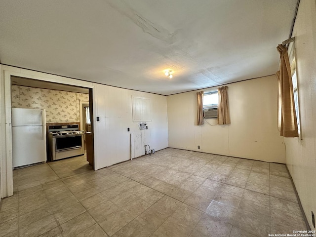 unfurnished bedroom with cooling unit and white fridge