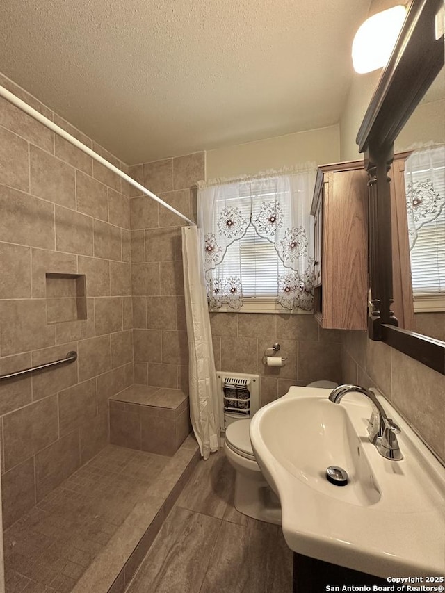 bathroom featuring toilet, a textured ceiling, tile walls, heating unit, and a shower with curtain