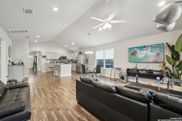 living room featuring ceiling fan with notable chandelier, light hardwood / wood-style flooring, and high vaulted ceiling