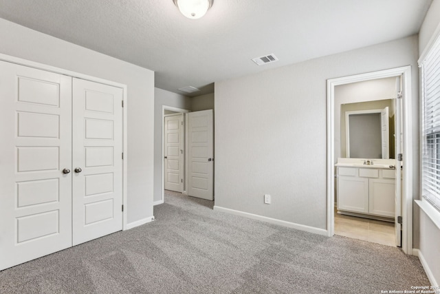 11559 Cottage Pt, San Antonio, TX 78254 - unfurnished bedroom featuring light colored carpet, connected bathroom, a closet, and a textured ceiling