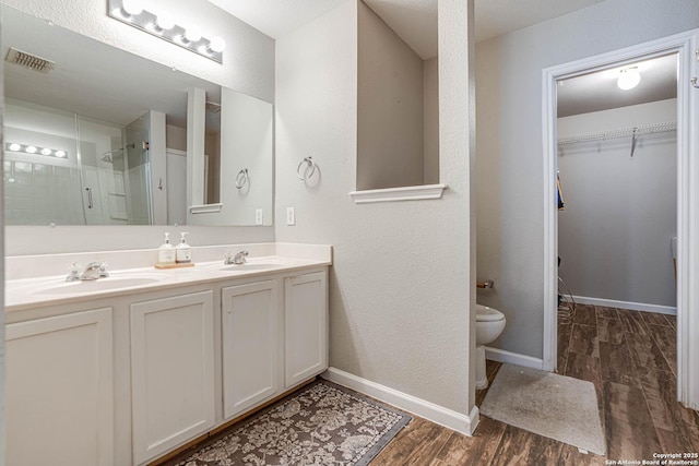 bathroom with wood-type flooring, an enclosed shower, vanity, and toilet