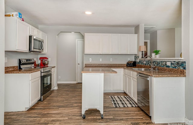 kitchen with a center island, white cabinetry, sink, dark wood-type flooring, and stainless steel appliances